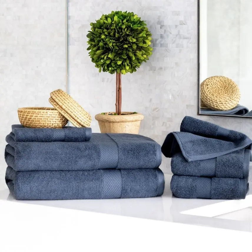 Stacks of blue Premium Turkish Cotton towels on a white surface with decorative items in the background.