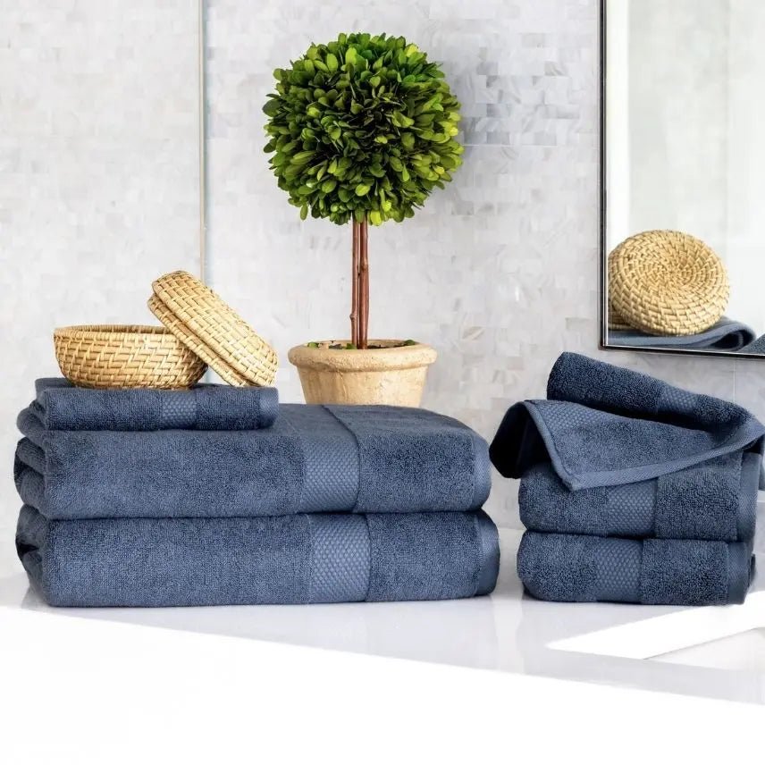 Stacks of blue Premium Turkish Cotton towels on a white surface with decorative items in the background.