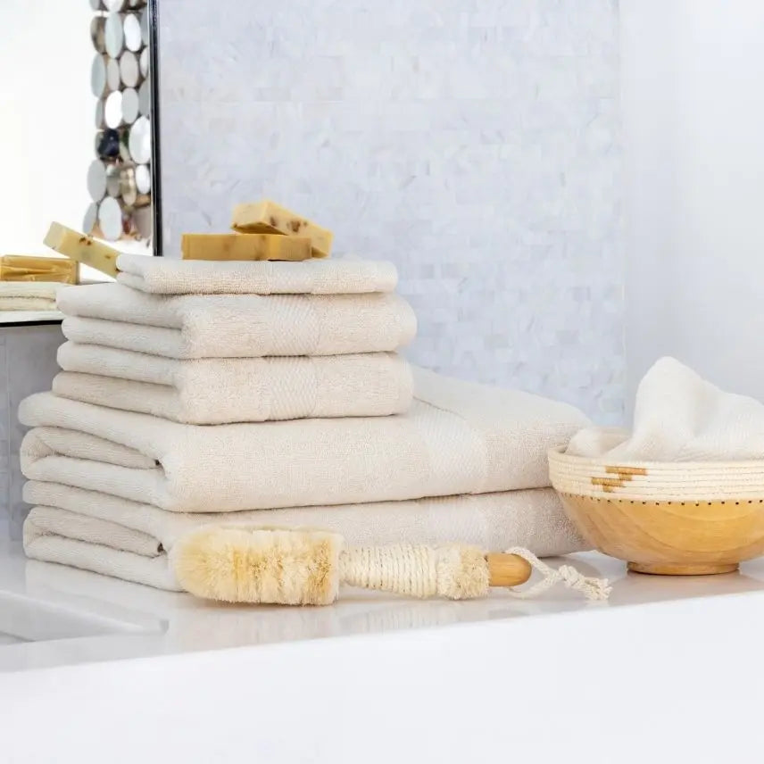 Stack of white Premium Turkish Cotton towels with a wooden brush on a light surface.