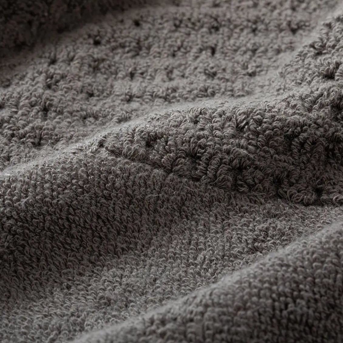 Close-up of textured gray waffle towel fabric with a focus on pattern and texture.