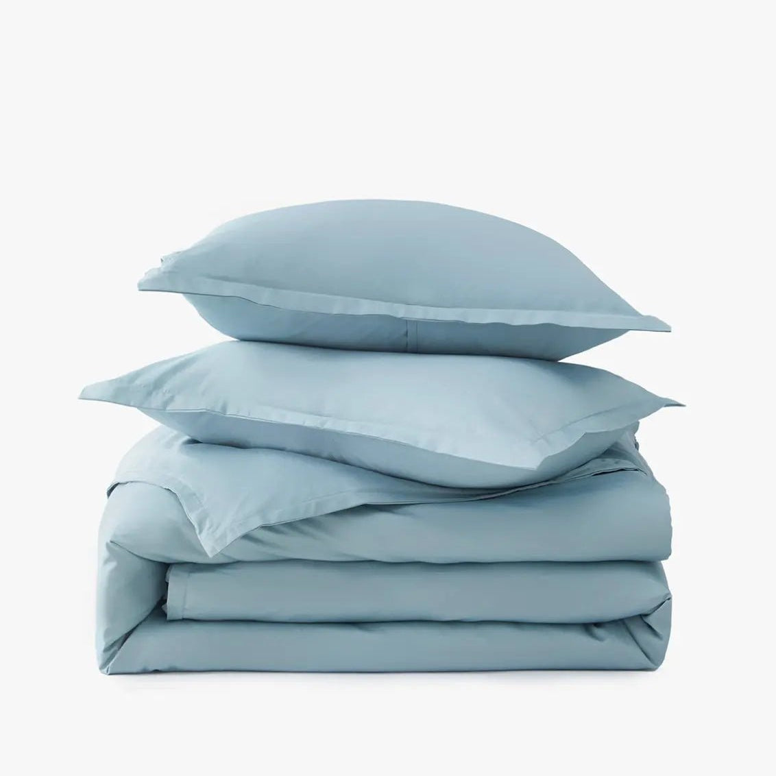 Stack of light blue bedding including a duvet and pillows on a white background