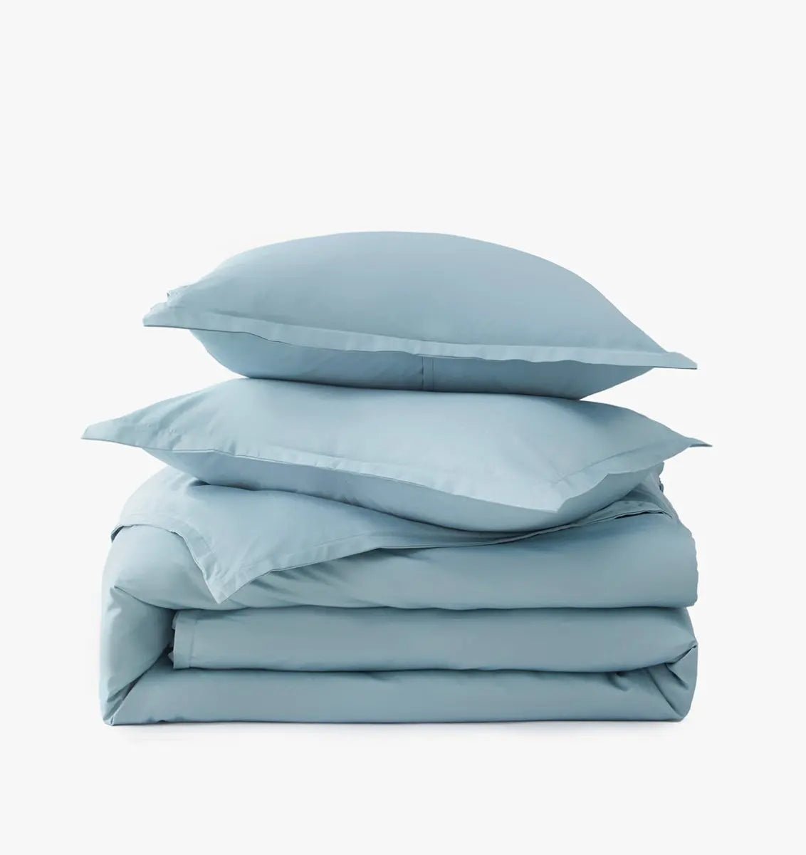 Stack of light blue bedding including a duvet and pillows on a white background