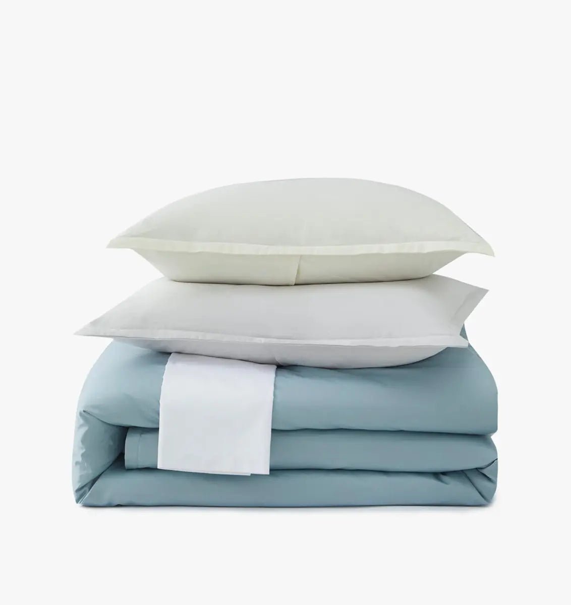 Stack of light blue bedding and white pillows on a white background