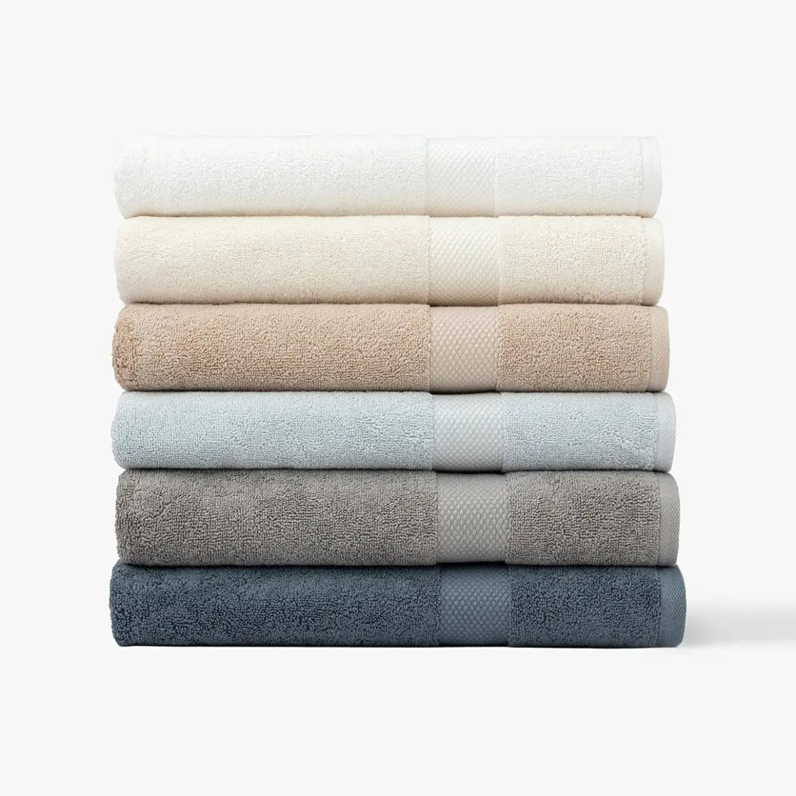 Stack of folded Premium Turkish Cotton towels in various colors on a white background