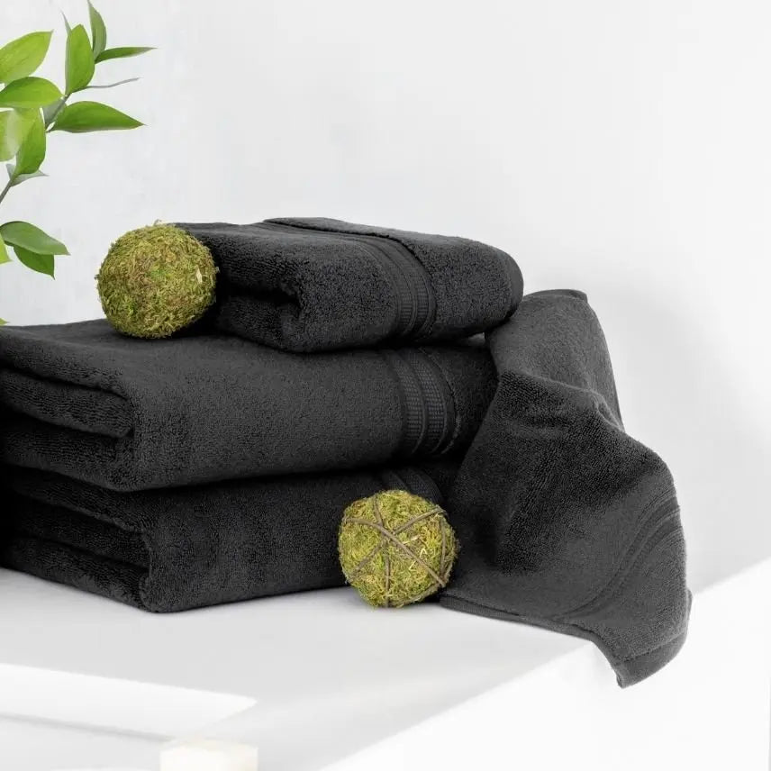 Stack of coal dark gray towels with green spherical objects on a white bathroom
surface