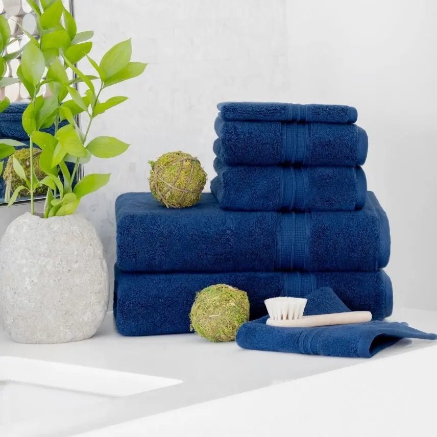Stack of blue towels on a white bathroom surface with decorative items.