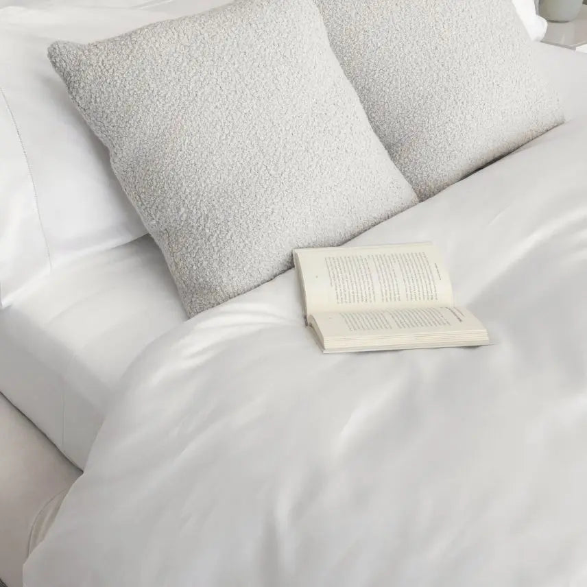White bedding on a bed with an open book