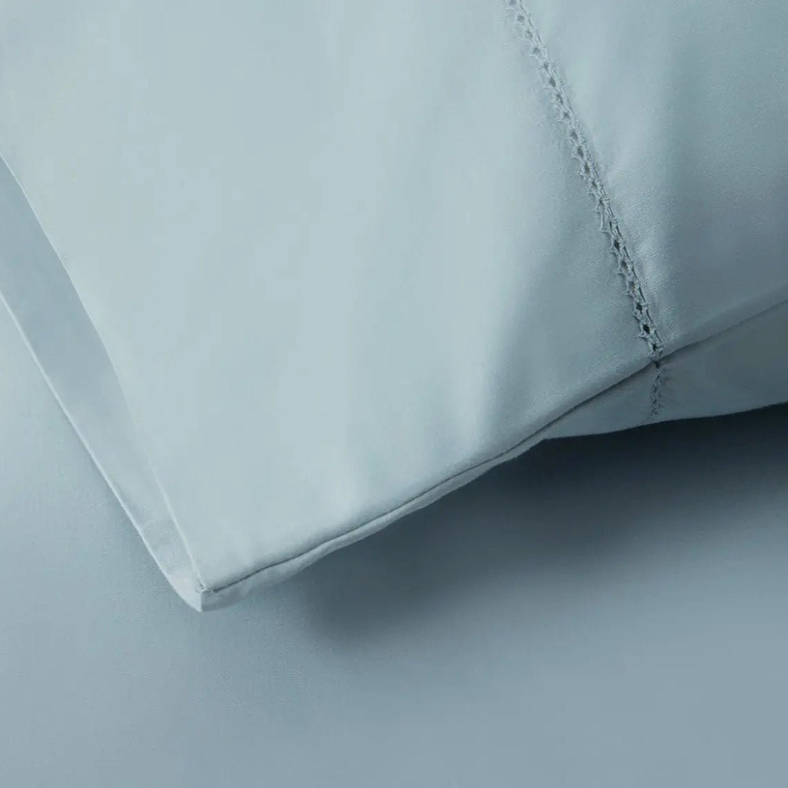 Close-up of a light blue bed sheet fabric with a subtle pattern
