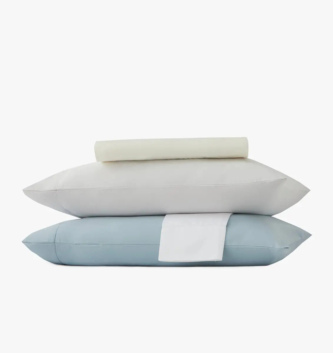 Stack of pillowcases and bed sheets in ivory, white and light blue on a white background