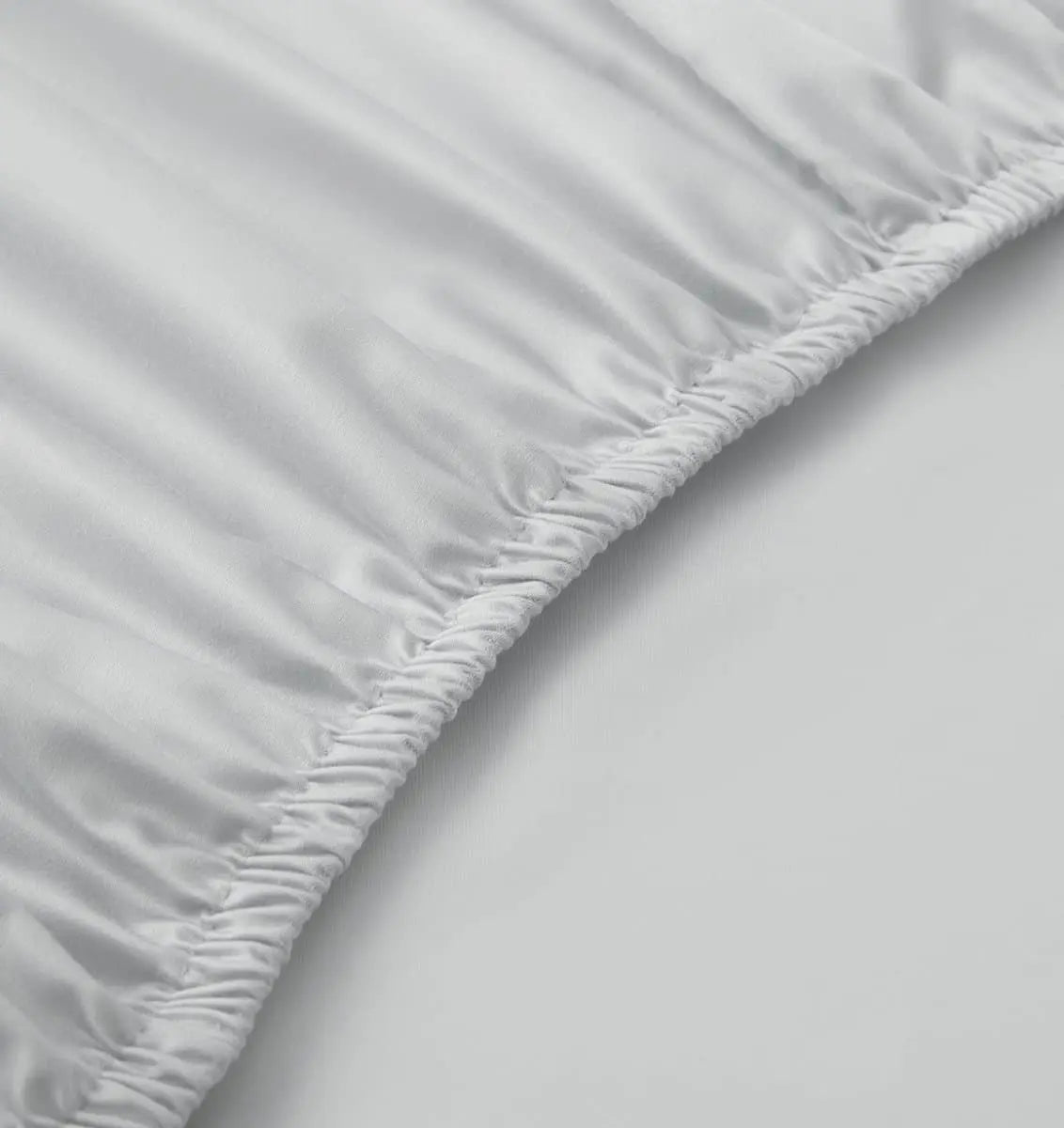 Close-up of a fitted sheet on a bed with a plain background
