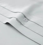 Close-up of a light gray bedding fabric with a button 