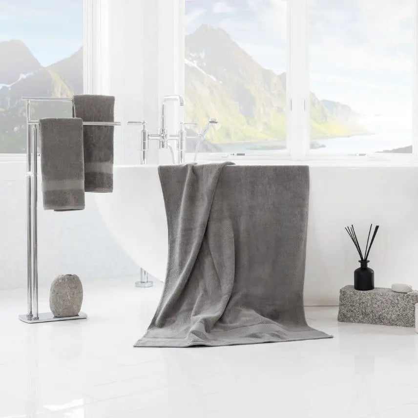 Premium Turkish Cotton Gray towel draped over a bathtub with a scenic view outside the window.