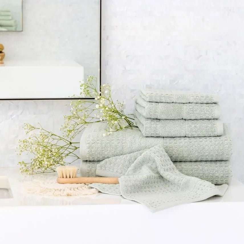 Stack of light mist green towels on a bathroom surface with decorative elements.