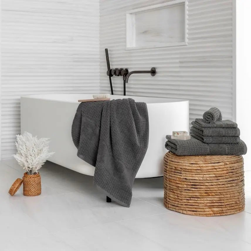modern Bathroom with a white bathtub, gray towels, and a wicker basket.