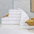 Stack of white towels on a bathroom counter with a brush and soap.