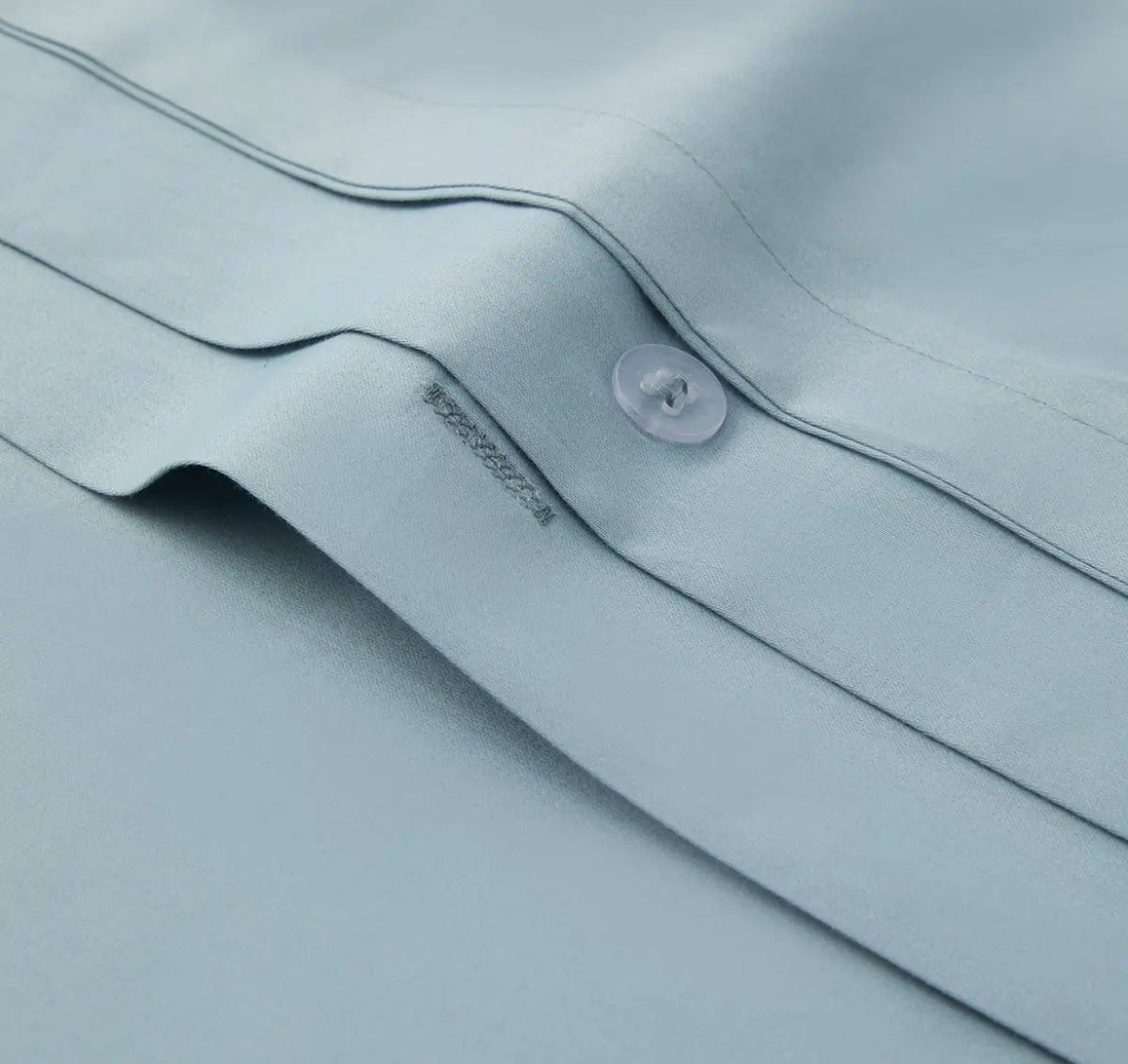 Close-up of a light blue bedding fabric with a button