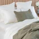 Bed with white and moss green bedding and pillows