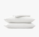 Stack of white pillow cases and sheets on a white background