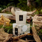 Voluspa Santal Vanille Classic Candle with box on a grassn and wood scenery