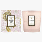 A Voluspa Panjore Lychee scented candle with a pink and white design on the packaging, featuring a floral pattern and a clear glass candle container.