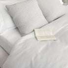 White bedding on a bed with an open book