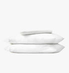 Stack of white pillows and bed sheets on a white background